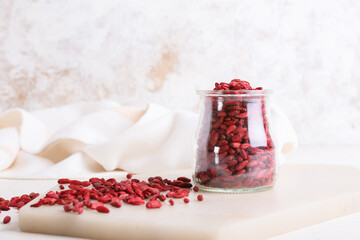 Jar with dried barberries on light background