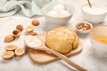 Wooden board of fresh dough for preparing walnut shaped cookies with boiled condensed milk and ingredients on light background