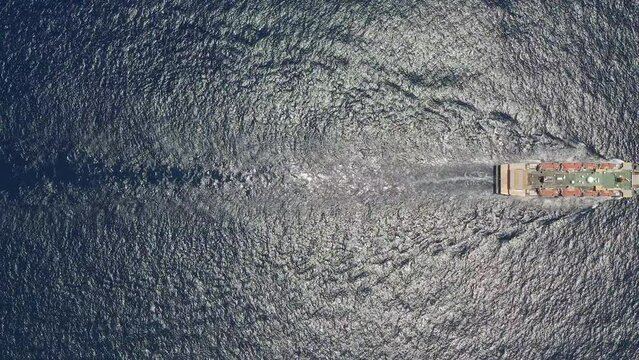 Aerial top view of cargo ship carrying container and running for export goods from cargo yard port to custom ocean concept freight shipping by ship. Large container ship at sea. Aerial top down.