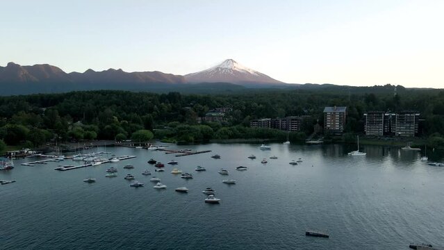 Aerial view of the villarrica volcano in pucon with boats parked on the lake - drone shot