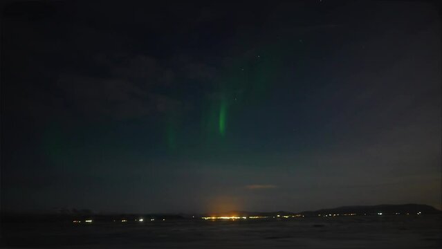 Panorama shot of emerging  Aurora Borealis over city of Reykjavik during night in Iceland