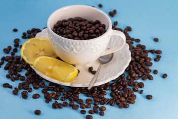 Coffee beans in a white mug on a saucer. There are lemon slices on a plate.