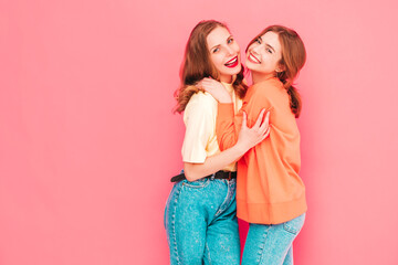 Two young beautiful smiling hipster female in trendy summer hipster  clothes. Sexy carefree women posing near pink wall in studio. Trendy and positive models having fun. Cheerful and happy