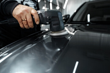 Car detailing. Male hands with orbital polisher in auto repair shop