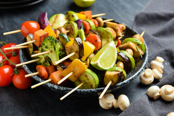 Bowl with tasty vegetable skewers on table, closeup