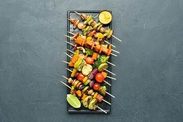 Plate with tasty vegetable skewers and mustard on dark background