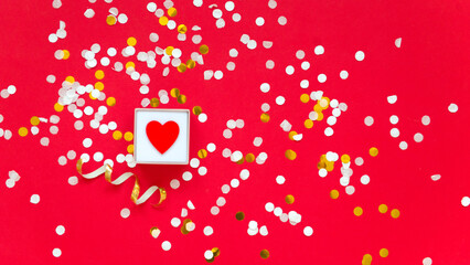 little red heart in box on red background with confetti