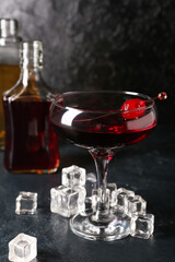 Glass of tasty Manhattan cocktail on black background