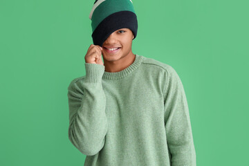 Handsome African-American guy in knitted sweater on color background