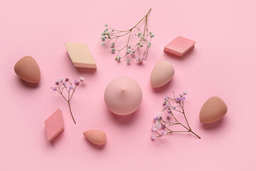 Different makeup sponges and flowers on pink background - obrazy, fototapety, plakaty