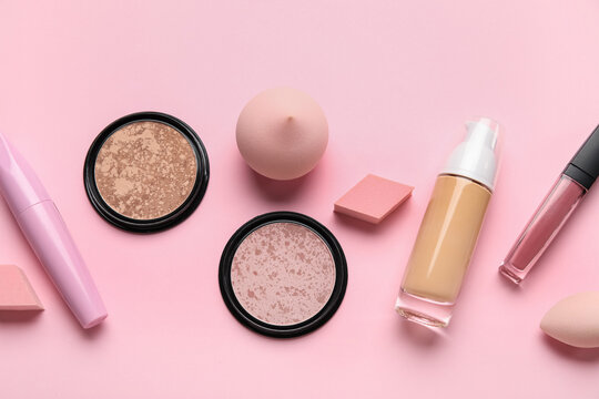 Makeup sponges and cosmetic products on pink background