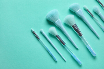 Set of makeup brushes on turquoise background