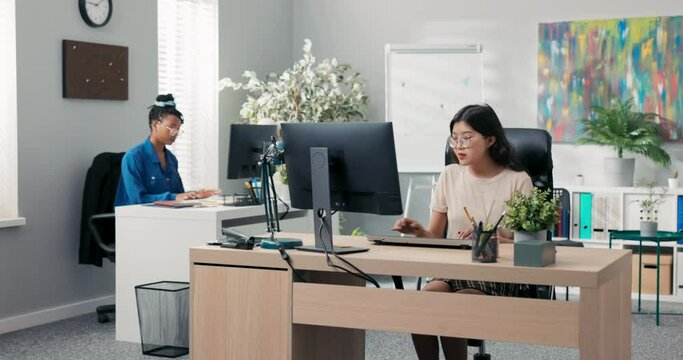 Busy afternoon at the office, accounting department, marketing, two elegant women work in front of computers, create documents, plan strategy, enter bills into the system