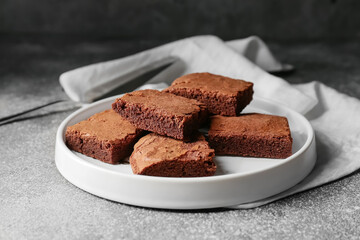 Plate with pieces of tasty chocolate brownie on grey background