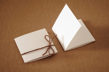 A square trifold mini card in his hands and lying on the table tied with a string