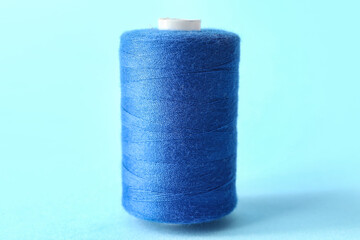 Blue sewing thread spool on color background