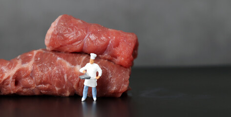 Uncooked beef and two miniature chefs. Miniature people and Uncooked beef with business concept.
