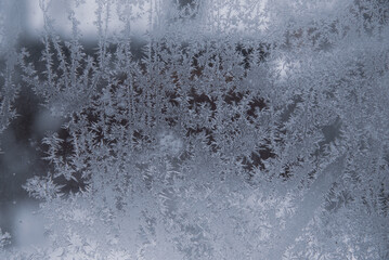 Frosty pattern on dirty window glass on a cloudy winter day.