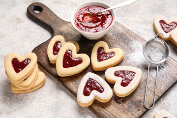Board with tasty cookies and jam for Valentine's Day celebration on light background, closeup