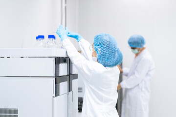 Unidentified operators are working in the chemical analysis equipment laboratory, concept of science, research and development of analytical technology in pharmaceutical industry.