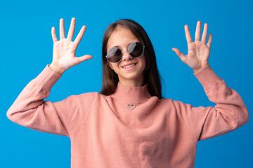Little fashion girl in sunglasses against blue background