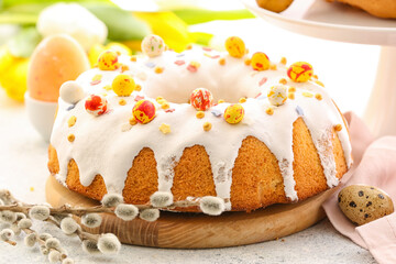 Wooden board with tasty Easter cake and pussy willow branches on table