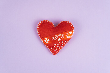 Top view Valentine's Day concept with copy space. Red textile heart on purple papper background
