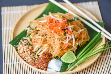 Thai food fried noodle Thai style with prawns bean sprout and garnish peanuts chili powder sugar lemon lime, Stir-fry noodle Pad Thai on plate served on the dining table food - top view