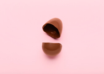 Broken chocolate Easter egg on pink background