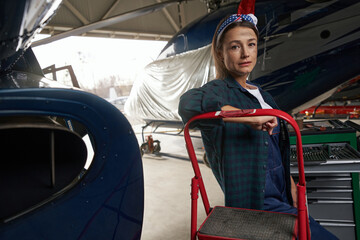 Naklejka premium Beautiful elegant female relief engineer working in aviation hangar