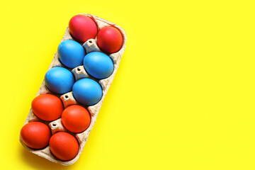 Obraz premium Holder with red and blue Easter eggs on color background