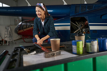 Female maintenance engineer in front of the private jet airplane in garage