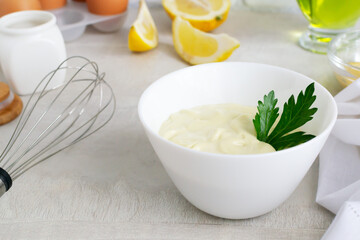 Homemade mayonnaise in a white bowl with ingredients in the background. The concept of proper drinking. Selective focus. Horizontal orientation.