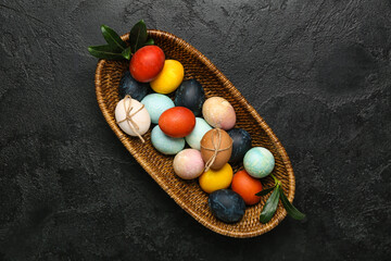Wicker basket with multicolored Easter eggs on dark background