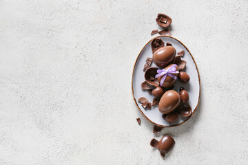Plate with chocolate Easter eggs on light background