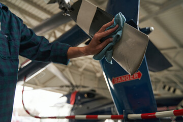 Female holding the microfiber in hand and polishing the parts of aircraft