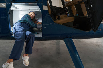 Woman mechanic in overall renovation and inspecting jet aircraft in hangar