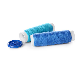 Blue thread spools and button on white background