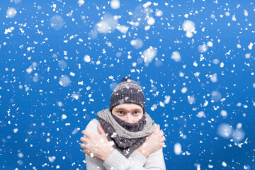 A frozen guy in a jacket and a scarf under the falling snow. Snow flakes. Coldly. A man is standing under the snow. Winter