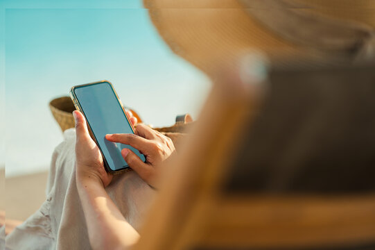 Young Asian woman using smartphone beside the pool at luxury hotel. technology and business concept background... - Powered by Adobe