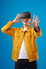 Happy millennial man in vr glasses playing and trying to touch something when exploring simulation of world