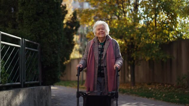Happy senior woman on walk with walker in city in winter.