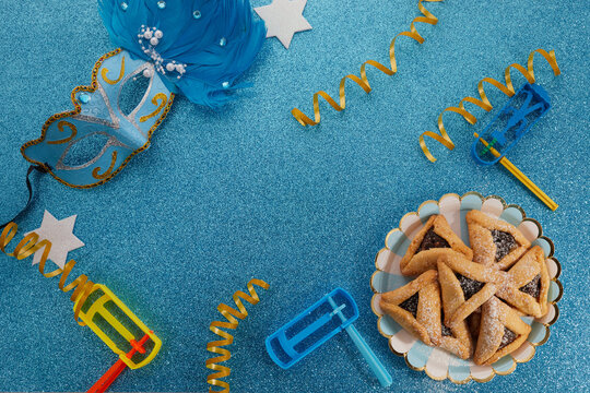 Jewish holiday Purim background with hamantaschen or hamans ears cookies, carnival mask and noisemaker