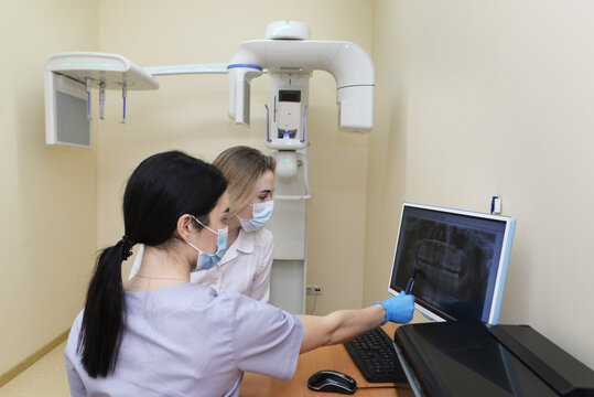 Dentist with an assistant look at the x-ray image of the jaw on the monitor