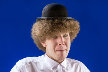 Handsome curly man in a small hat. Humor. Cool guy. A funny student. Facial expressions.