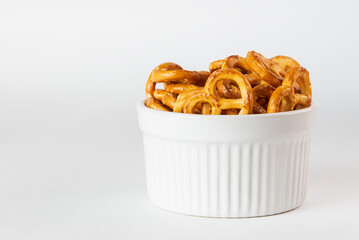 Salted pretzels in a white bowl close up. Option of serving snacks or crackers on a white background