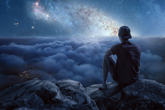 Man on a mountain looking at a beautiful starry night sky