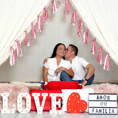 Latino adult man woman couple demonstrate love under a teepee with a sign that says 