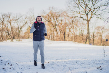 Fototapeta na wymiar Adult man is exercising in park in wintertime. He is jogging.