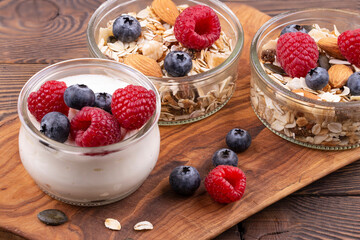 Homemade granola with nuts, raspberries and blueberries, yogurt on a wooden rustic table, copy space. healthy breakfast